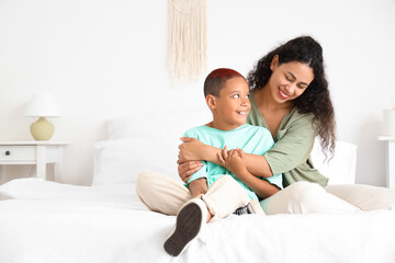 Fototapeta premium Little African-American boy with his mother hugging in bedroom