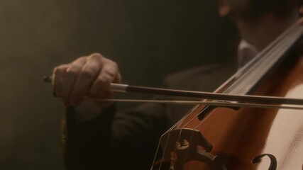 Cropped shot of unrecognizable male musician in suit performing music with cello on black background