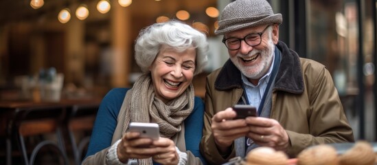Fototapeta premium Elderly Couple Laughing Together While Using Smartphones