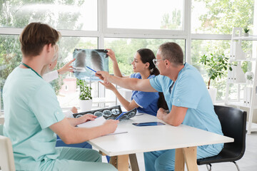 Obraz premium Group of doctors studying x-ray image of lungs at table in clinic