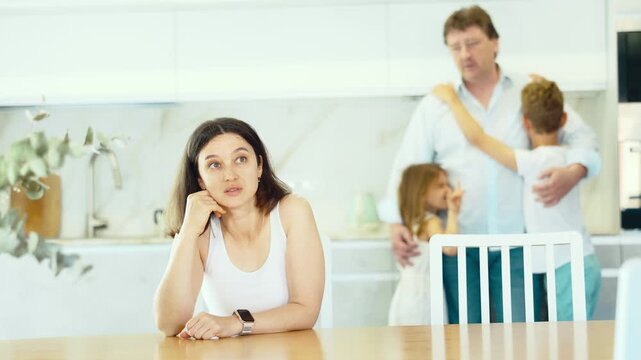 Offended wife sits at the table and listens as her husband yells at her. High quality 4k footage