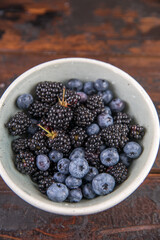 Ripe black blackberries and blue blueberries on a wooden table