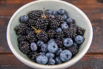 Ripe black blackberries and blue blueberries on a wooden table
