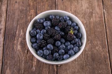 Ripe black blackberries and blue blueberries on a wooden table