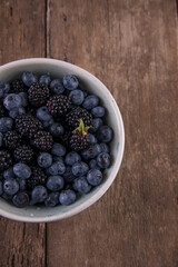 Ripe black blackberries and blue blueberries on a wooden table