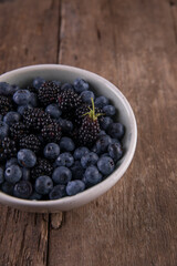 Ripe black blackberries and blue blueberries on a wooden table
