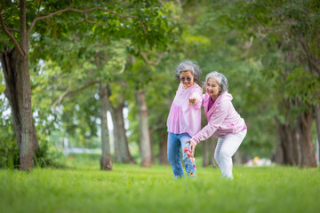 Fototapeta premium Two Elderly Women Exercising Outdoors in a Tree-Lined Park, Embracing Health and Friendship