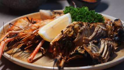 Close-up view of delicious seafood platter featuring grilled shrimps, lobsters, wedge of lemon, and fresh parsley on plate, great for gourmet cuisine, culinary, dining. Seafood and Gourmet Cuisine.
