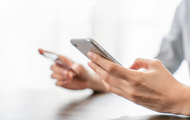 Woman hand holding a credit card and using smartphone to pay online. The concept of online shopping and payment.