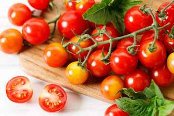 Cherry tomatoes with vines on wooden plank.