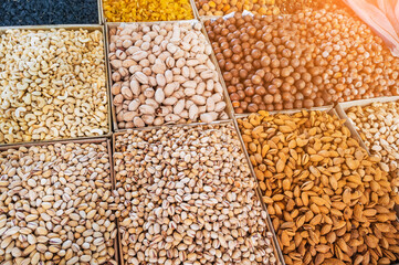 assortment of different variety nuts and dried fruits on counter at oriental bazaar. Almonds, raisins, pistachios, hazelnuts, macadamia in market stall
