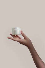 Female hand holds cream jar for cosmetics. Packaging for cream, gel, serum, advertising and product promotion, mock up           