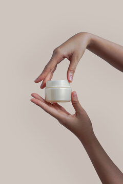 Female hands holds cream jar for cosmetics. Packaging for cream, gel, serum, advertising and product promotion, mock up           