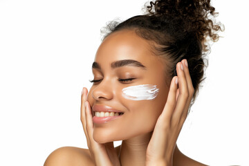woman with curly hair is applying makeup to her face. She is smiling and she is in a relaxed and happy mood