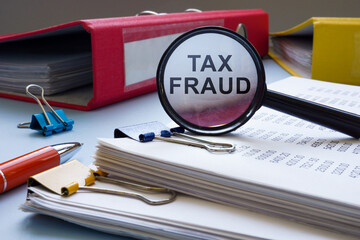 Tax fraud concept. Financial statement papers and a magnifying glass.