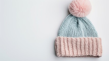 A cozy knitted hat with a large pom-pom, in soft pastel colors, isolated on a white background with ample copy text space