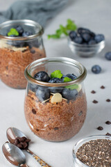 Healthy food: Chocolate chia pudding with blueberry and almonds in glass jars on gray background