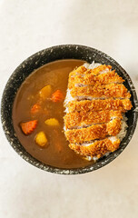 Japanese chicken katsu curry rice, Deep fried chicken fillet with carrot and potato curry in black plate on wooden table Crispy fried chicken cutlet with curry rice - Japanese food style