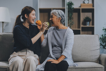 Happy asian woman daughter hugging senior mother in the kitchen room eating healthy food happy enjoying.