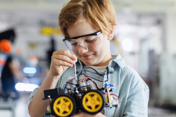 Portrait of schoolboy building robotic car in after-school robotics club. Children learning...
