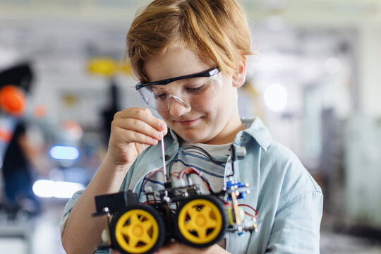 Portrait of schoolboy building robotic car in after-school robotics club. Children learning robotics in Elementary school. Science for kids.