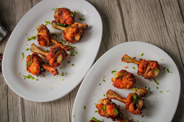 Chicken lollipop deep fried in oil. Later garnished with green coriander and onion.