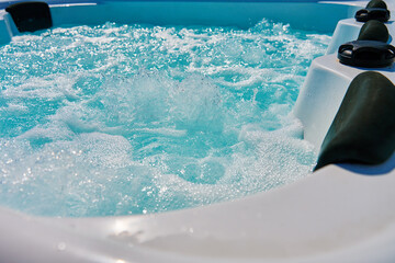 Close-up shot bubbling water in hot tub with headrests. Blue water in jacuzzi for relaxing and...