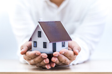 Businessman hand hold the house model is destination and goal and success to give of loan in the office, Loan and investment the real estate concept.