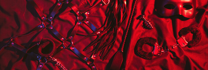 set of BDSM sex toys with handcuffs, whip flogger, butt anal plug for submission and domination on...