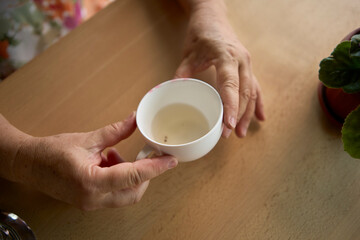 60s woman drinking nettle tea in modern coworking office during lunch break
