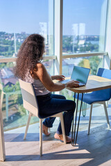 A 57-year-old woman works on a laptop in a modern office workspace