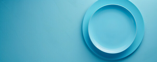 Celebration concept with a blank sky blue plate on a sky blue table, viewed from above. The light sky blue evokes a calm atmosphere. Plenty of room for text.