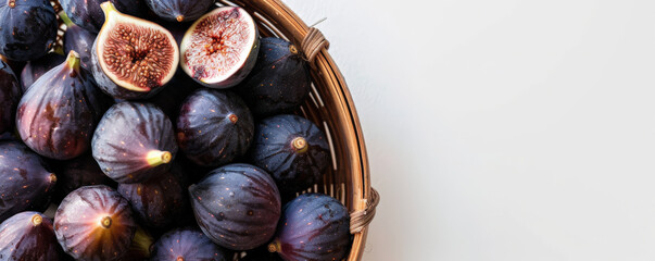 Obraz premium A wooden basket filled with fresh organic figs, with plenty of text space on a clean, white background.