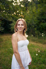 portrait of a beautiful 30-year-old woman in a white dress in the garden