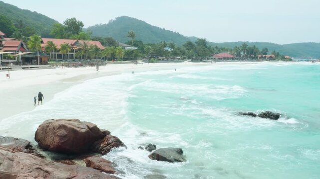 Tourists enjoying a leisurely walk on the beach at redang island, malaysia