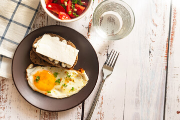 Fried eggs in plate with tomatoes salad and cheese sandwich for breakfast