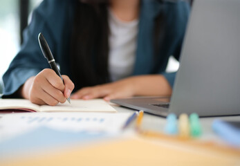 A woman is writing in a notebook with a pen