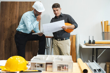 Architecture and teamwork concept. Male engineers or business partners on a construction site, discussing project details.