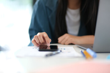 A woman is using her cell phone while sitting at a desk