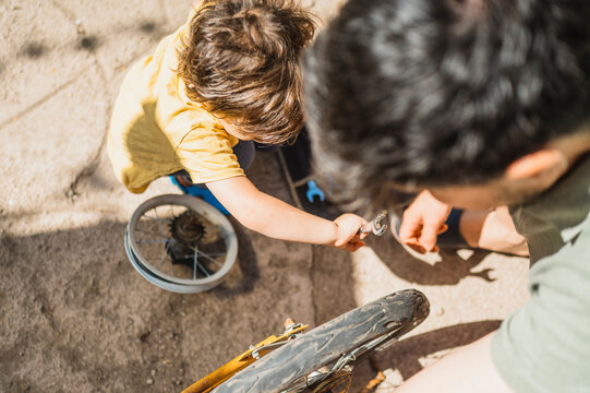 Father and son repairing old bicycle in back yard