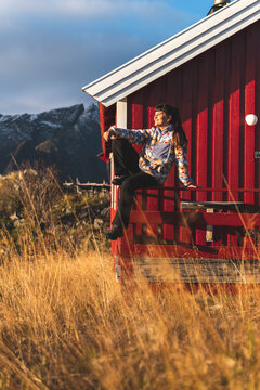 Happy woman resting on railing of log cabin