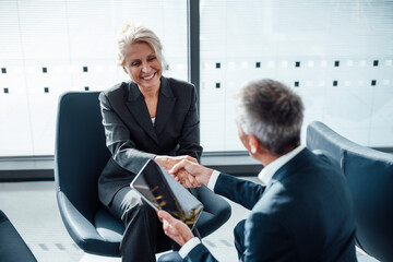 Smiling businesswoman doing handshake with colleague at office