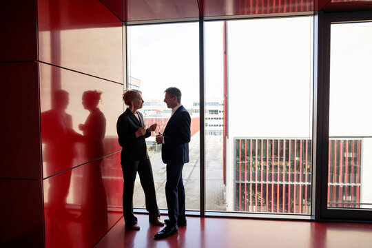 Senior business colleagues talking near red wall
