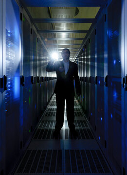 Security staff with flashlight standing in illuminated server room