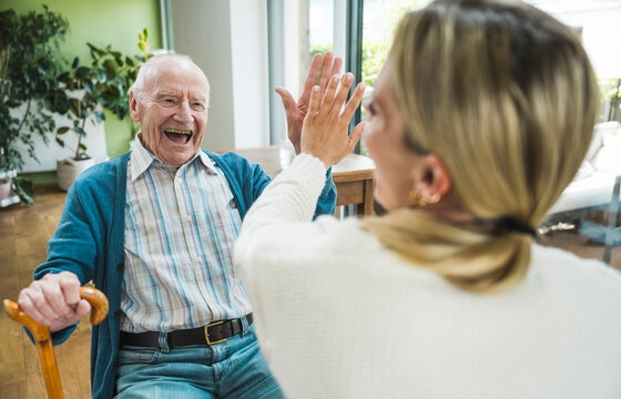 Happy senior man giving high-five to woman at home