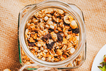 Granola in a jar against the background of canvas fabric. Ideal for a healthy breakfast