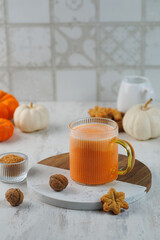 Pumpkin Spice Latte and Cinnamon Bun for breakfast on light grey background. Cup of coffee and homemade cookies with seasonal autumnal leaves, copy space. Vertical