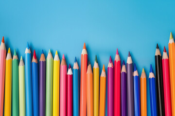 A colorful array of colored pencils is neatly arranged on a light blue background, ready for creative use. Light blue background