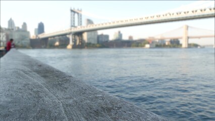 New York City Manhattan Bridge to Dumbo, Brooklyn Bridge. Defocused waterfront skyline cityscape, fisherman on riverfront Pier 35, USA. East river view, people and morning sunset, man fishing by water