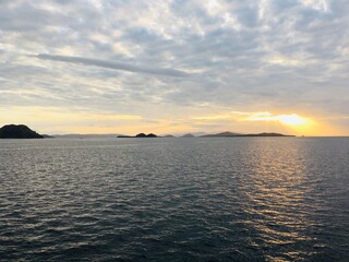Obraz premium Evening Light Reflecting on Calm Sea with Distant Island